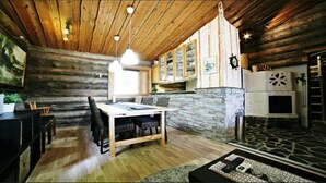 A rustic interior with a wooden dining table, stone accents, and a fireplace. - Kivikoski riverside cottage in Pyhtää for 5-8 people (Pyhtää)