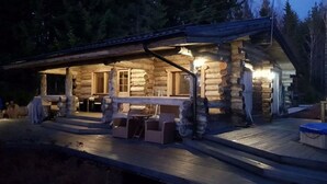 A log cabin with a porch, outdoor seating, and a well-lit interior. - Kivikoski riverside cottage in Pyhtää for 5-8 people (Pyhtää)