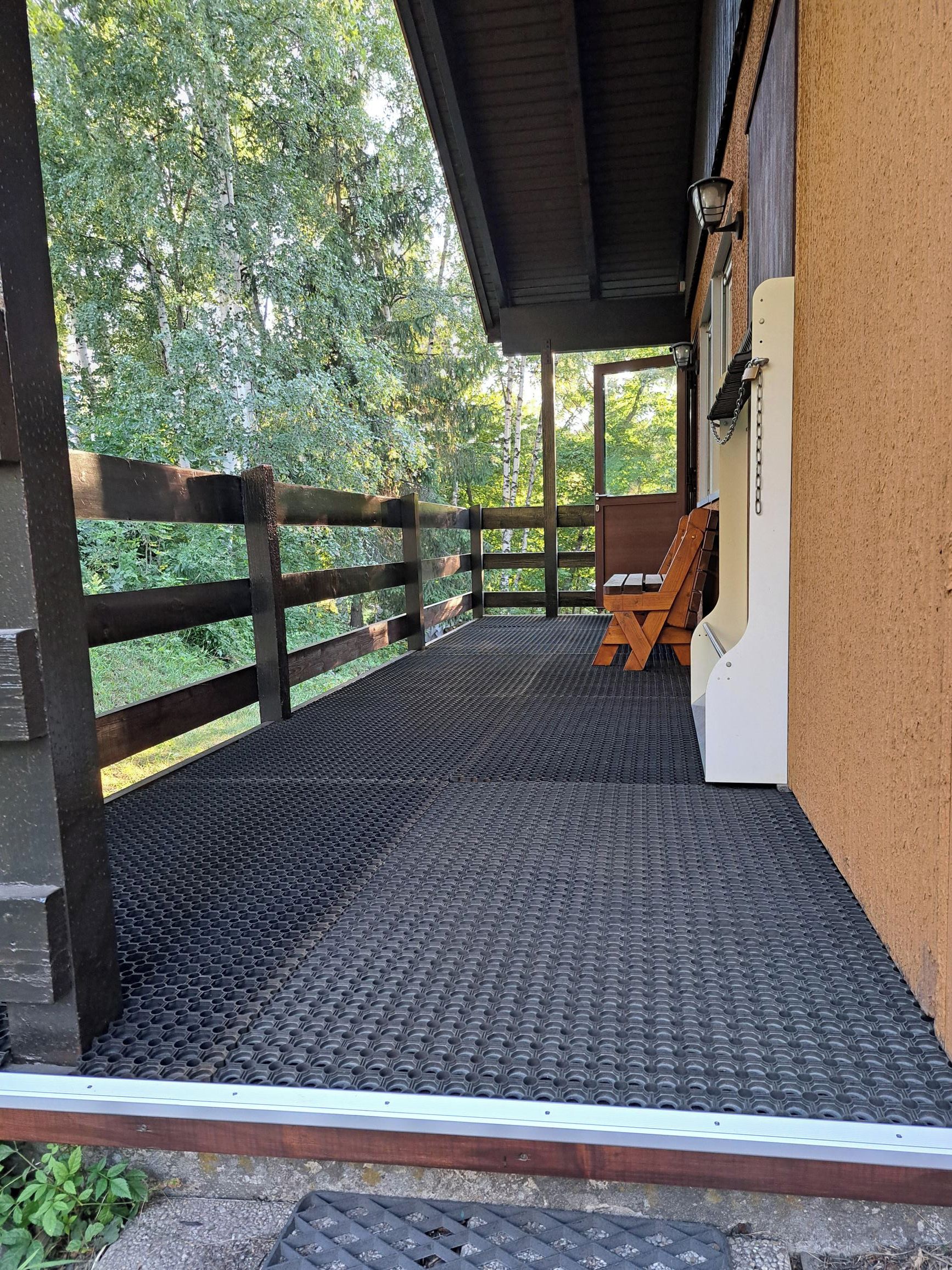 Un espace extérieur abrité, avec un banc en bois et un barbecue en métal.