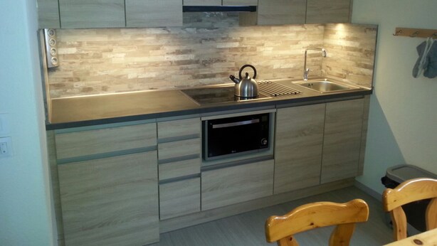 A modern kitchen with wooden cabinets, a stainless steel sink, and a kettle on the countertop. - Detached chalet on the slopes and near the village, for winter sports & summer holidays (La Norma)