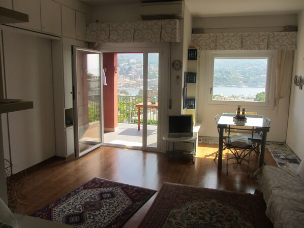 Una sala de estar con balcón, comedor y vista a un cuerpo de agua.