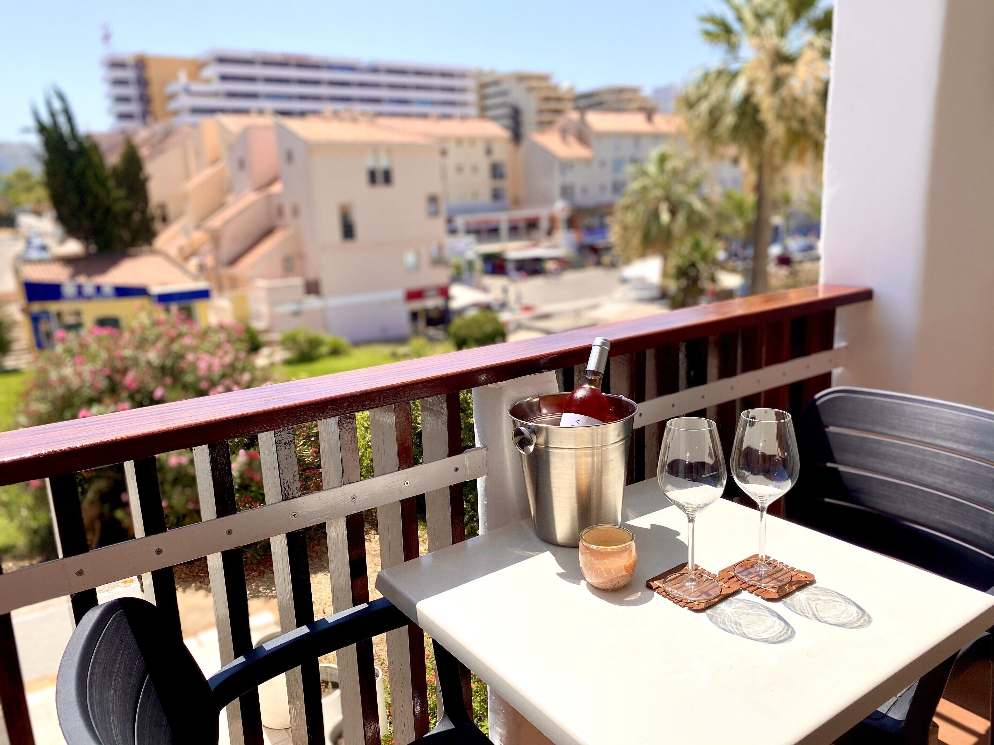 A balcony with a table set for two, a wine bottle, and two wine glasses.
