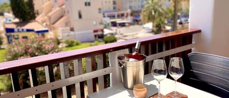 A balcony with a table set for two, a wine bottle, and two wine glasses.