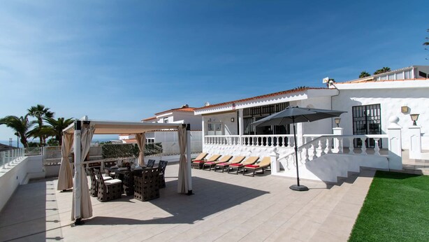 Une terrasse sur le toit avec des espaces de détente en plein air, une pergola et un espace piscine.