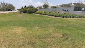 A sign for Rose Hall with a well-maintained lawn and a fence. - Bev ROSEVILLA 3 Bedroom family house in Rosehall Rhyne Park Village.Montego Bay  (montego Bay)