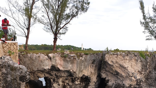 A natural pool surrounded by rocky cliffs, with people standing by the edge. - Bev ROSEVILLA 3 Bedroom family house in Rosehall Rhyne Park Village.Montego Bay  (montego Bay)