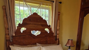 A bed with a wooden headboard, a striped bedspread, and a nightstand with a lamp. - Bev ROSEVILLA 3 Bedroom family house in Rosehall Rhyne Park Village.Montego Bay  (montego Bay)
