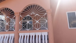 A building facade with arched windows featuring intricate lattice designs and a balcony with a white balustrade. - Bev ROSEVILLA 3 Bedroom family house in Rosehall Rhyne Park Village.Montego Bay  (montego Bay)