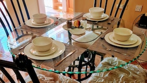 A dining table set with white plates, bowls, and cutlery, surrounded by chairs. - Bev ROSEVILLA 3 Bedroom family house in Rosehall Rhyne Park Village.Montego Bay  (montego Bay)
