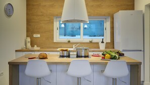 A modern kitchen with a wooden countertop, stainless steel appliances, and white bar stools. - Beautiful brand new villa ***** with heated swimming pool, summer kitchen, WiFi, grill (Pula)