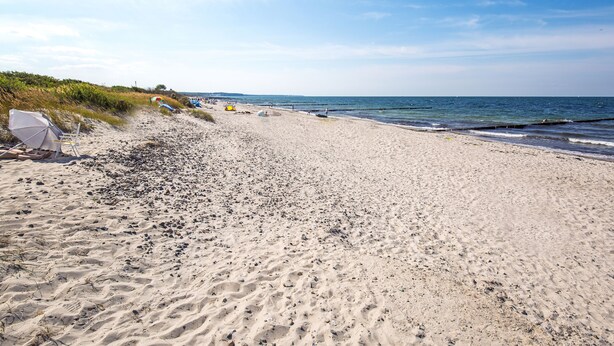 Une plage de sable avec des parasols et des chaises de plage.