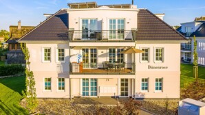 Un bâtiment à deux étages doté d’un balcon, d’une plaque signalétique portant l’inscription « Dünenrose », et d’une pelouse bien entretenue.