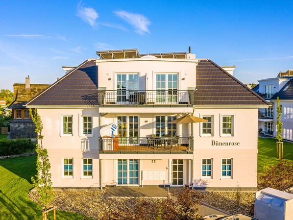 A two-story building with a balcony, a mailbox, and a well-maintained lawn. - Comfortable 3-room apartment, sea view balcony and 200 m to the beach (Börgerende)