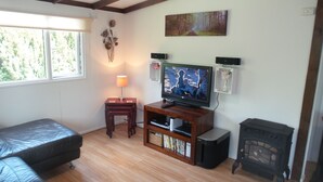 A cozy living room with a television, wooden entertainment unit, and a fireplace. - Beautiful river front self catering holiday lodge. (Builth Wells)
