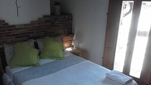 A bedroom with a bed, pillows, a nightstand, a lamp, and a brick wall. - Self catering El Rincon de Zaldierna for 4 people (Ezcaray)