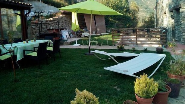 A patio area with a table and chairs, a green umbrella, and a stone wall. - Self catering El Rincon de Zaldierna for 4 people (Ezcaray)