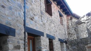 A stone building with a wooden door and windows, featuring a stone wall and a blue roof. - Self catering El Rincon de Zaldierna for 4 people (Ezcaray)