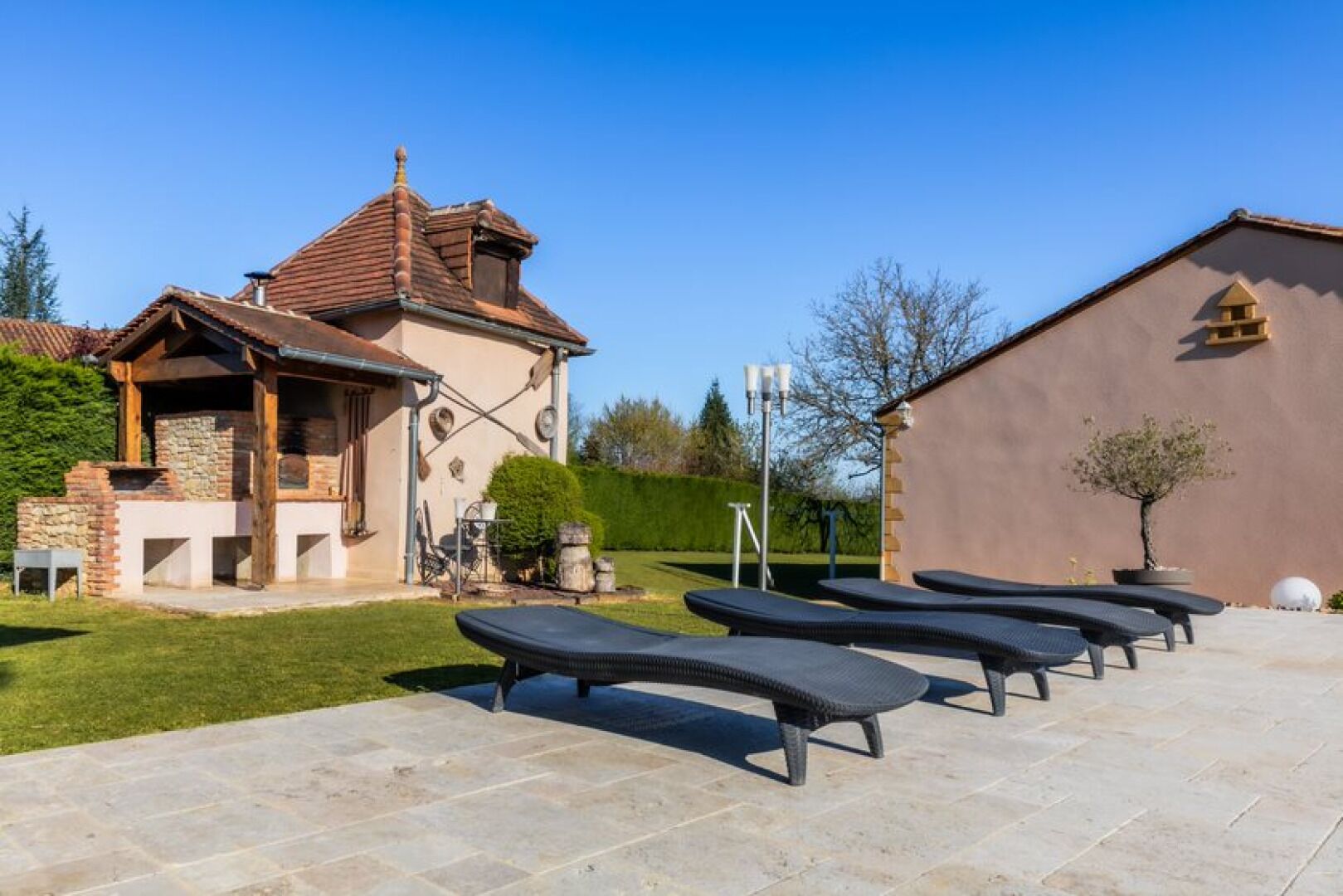 Ein Haus mit einer Terrasse, Sonnenschirmen und einem gepflasterten Weg.