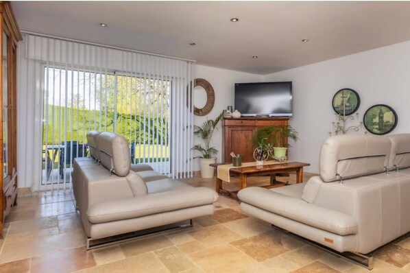 A living room with two beige sofas, a wooden coffee table, a TV, and a sliding glass door leading to an outdoor area.