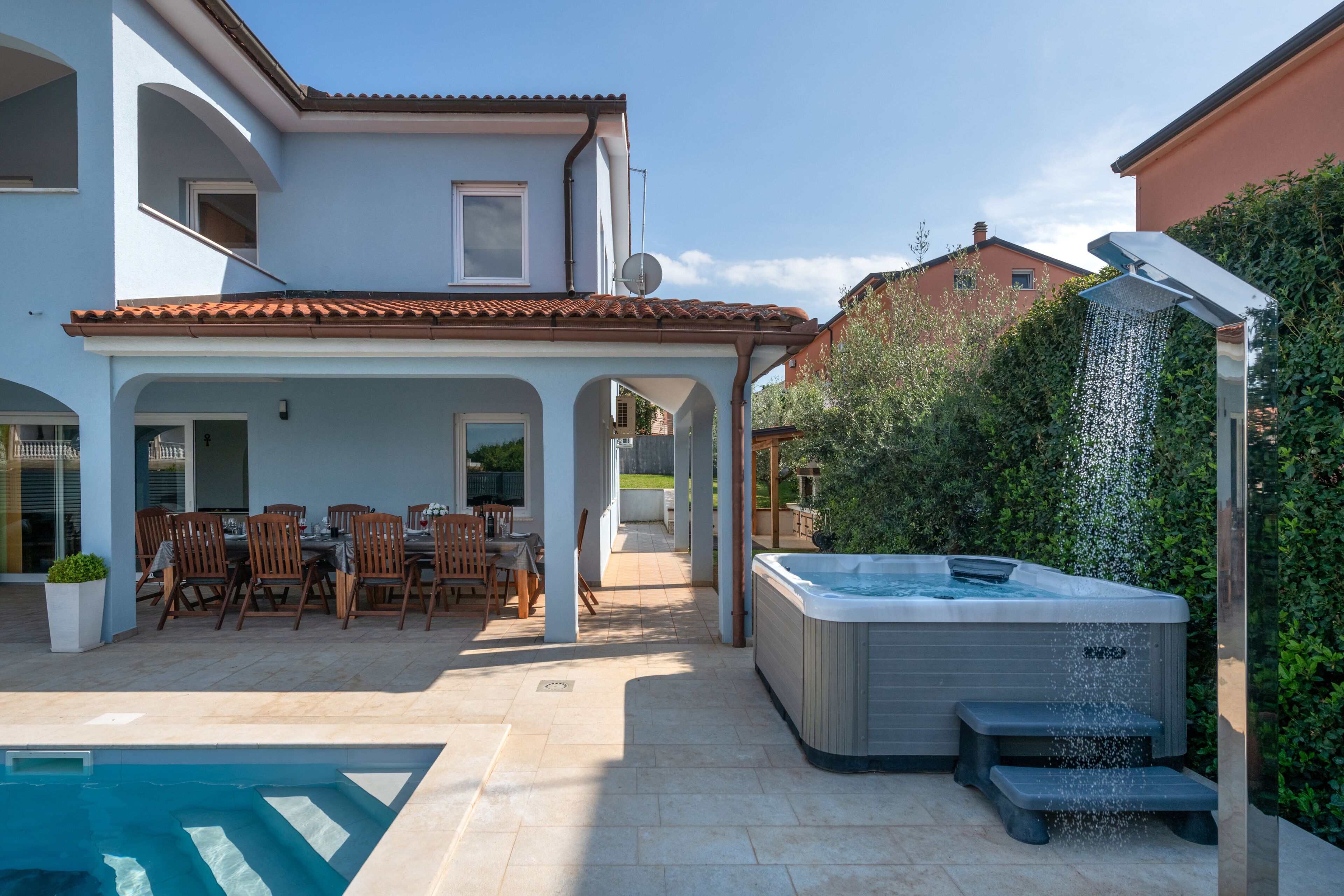 Une maison moderne dotée d’une piscine, d’un espace salon extérieur et d’un jacuzzi.