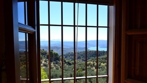 A room with a large window offering a view of a mountainous landscape and a body of water. - Self catering El Rincón de Carmen for 4 people (Rute)