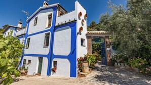 A two-story building with a blue and white facade, a stone entrance, and potted plants. - Self catering El Rincón de Carmen for 4 people (Rute)