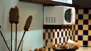 Un comptoir de cuisine avec un four à micro-ondes, un saladier rempli de fruits et un verre avec une paille.
