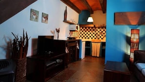 Un salon chaleureux avec une cheminée, des meubles en bois et un motif à carreaux sur un des murs.