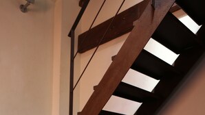 Un escalier avec des rampes en bois et un poêle à bois noir placé dans un coin.
