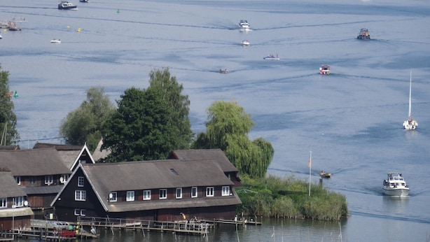 Ein Anwesen am Wasser mit Anlegesteg, Booten und einem Haus mit Strohgedeck.