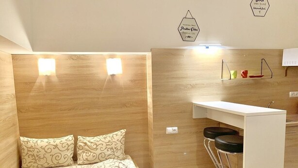 A compact room with a bed, a small kitchenette, and a wall-mounted shelf. - Smart Apartment Krehivska 7 (Lviv)