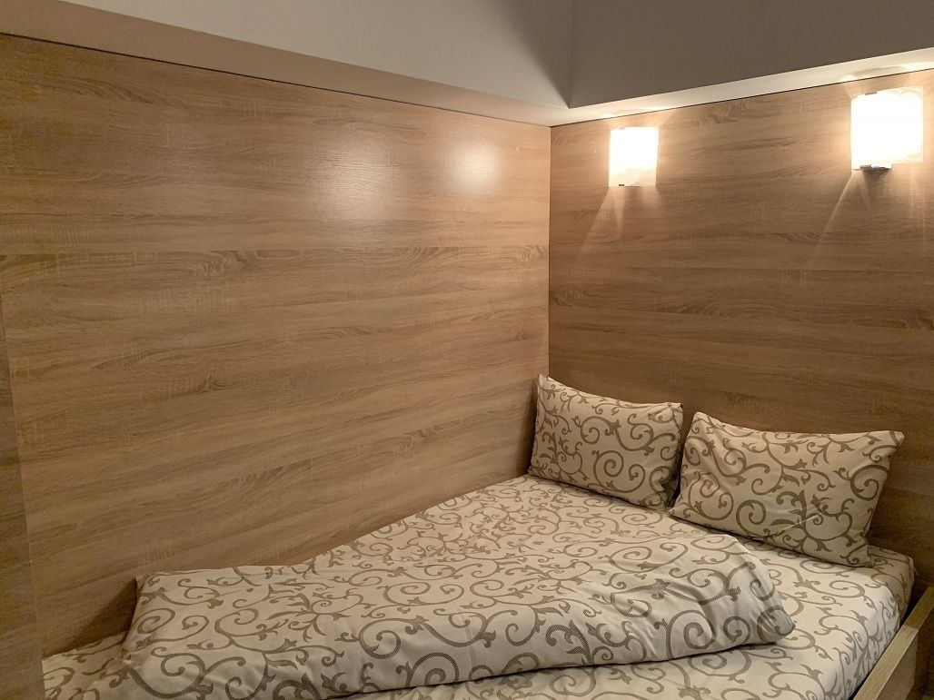 A bedroom with a wooden headboard, two bedside lamps, and patterned bedding.