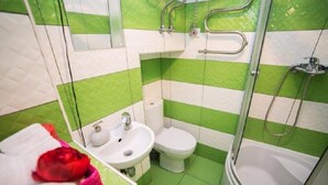 A bathroom with green and white striped tiles, a white sink, a toilet, and a shower. - Smart Apartment Krehivska 7 (Lviv)