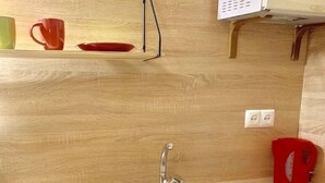 A modern kitchen with a stainless steel sink, wooden cabinets, and a microwave. - Smart Apartment Krehivska 7 (Lviv)