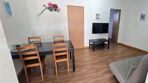 Un área de comedor con una mesa y sillas, un sofá, un televisor y una puerta.