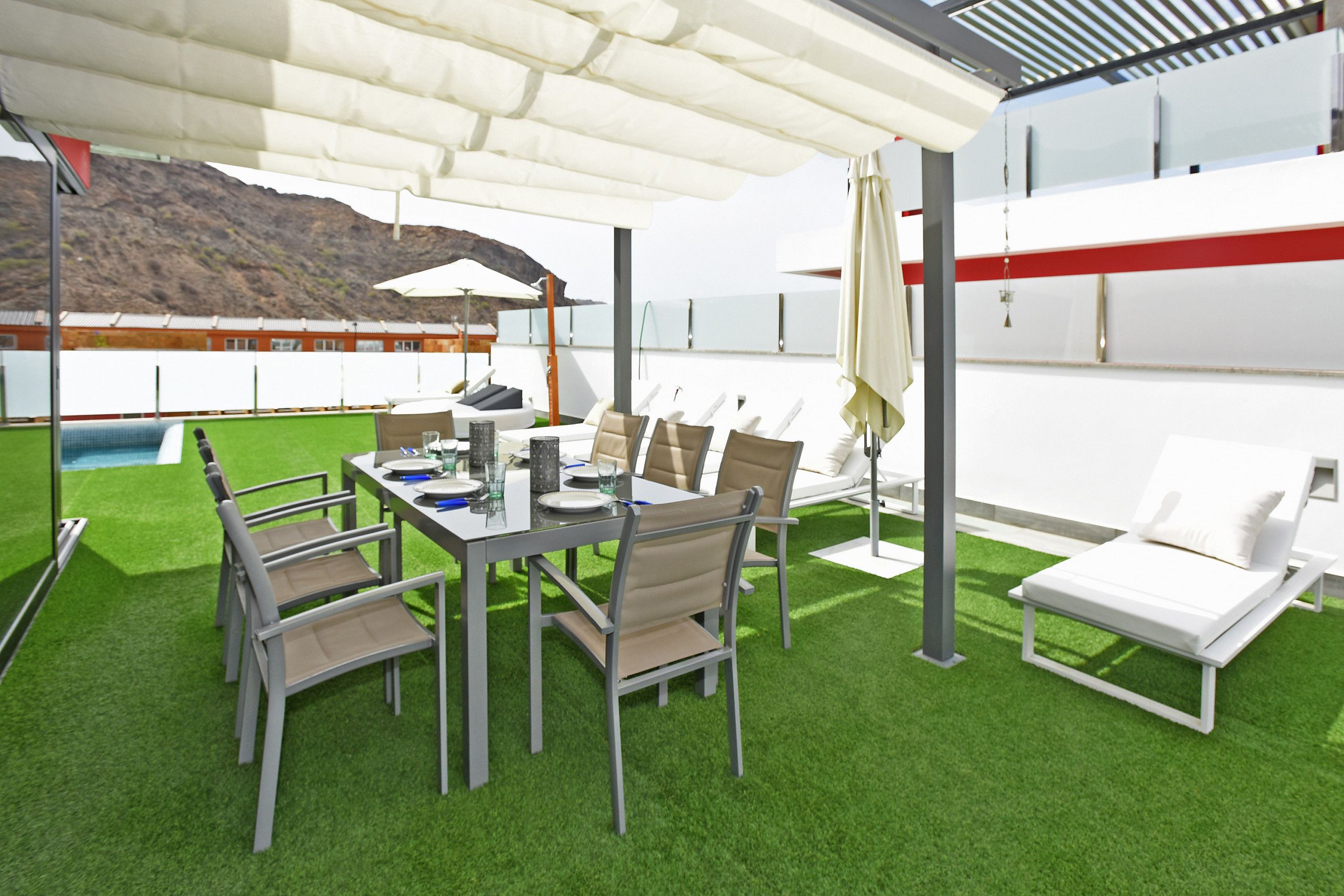 Eine Dachterrasse mit Esstisch, Stühlen und Liegestühlen.