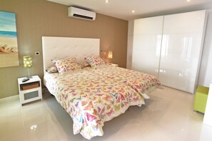 A bedroom with a large bed, a nightstand, a wall-mounted air conditioner, and a wardrobe. - Villa Morro del Guincho 29 (Mogán)