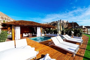 A poolside area with lounge chairs, a small pool, and a thatched-roof structure. - Villa Morro del Guincho 29 (Mogán)