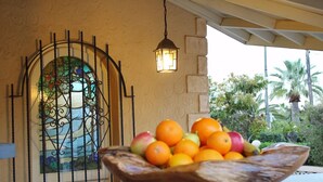 A wooden bowl filled with oranges and apples on a counter with a stone wall and a metal gate in the background. - Stylish Finca Julia with 1000 sqm garden, priv. Pool, Air, BBQ, fireplace, terrace (Denia)