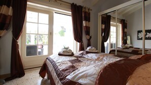 A bedroom with a large bed, a window with curtains, a mirror, and a view of the outdoors. - Stylish Finca Julia with 1000 sqm garden, priv. Pool, Air, BBQ, fireplace, terrace (Denia)