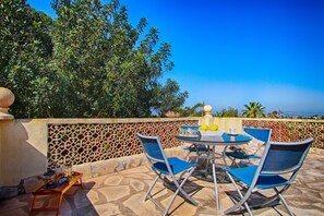 Relax on the patio with a round table and four chairs, surrounded by lush greenery.