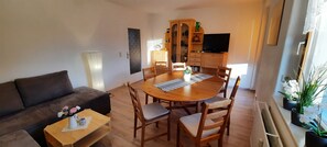 Un salon confortable avec un canapé, une table à manger et des chaises, un téléviseur et un meuble avec des portes en verre.