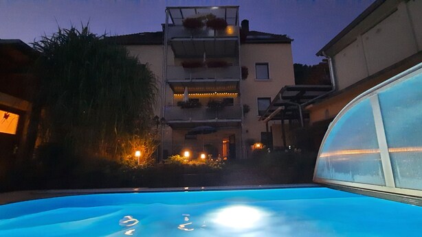 A swimming pool with a clear view of a multi-story building in the background. - Apartment with garden and pool use (Rathmannsdorf)