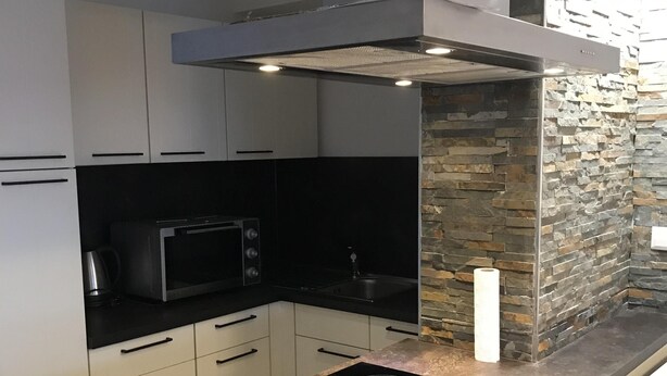 Une cuisine moderne dotée d’une cuisinière encastrée, d ’un four à micro-ondes et d’un mur décoratif en pierre.