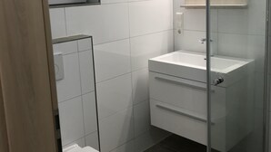 Une salle de bain moderne équipée de toilettes, d’un lavabo et d’une douche.