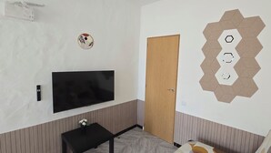 Ein Zimmer mit einem an der Wand befestigten Flachbildfernseher, einer Holztür und einem dekorativen sechseckigen Wandmuster.