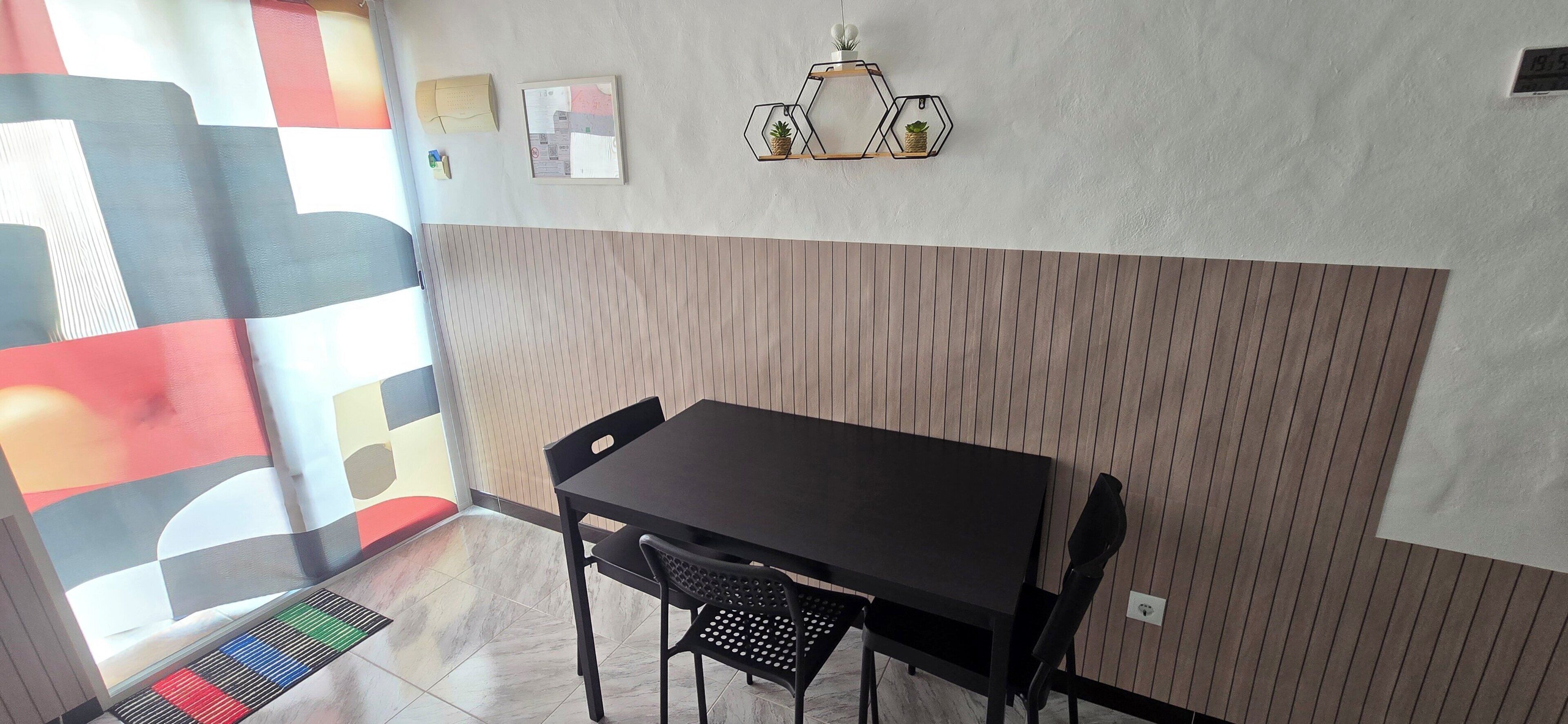 A dining area with a wooden panel wall, a black table, and chairs.