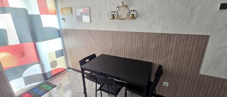 A dining area with a wooden panel wall, a black table, and chairs.
