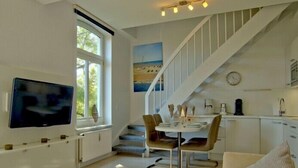 Eine moderne Küche mit Essbereich, einer Treppe und einem an der Wand befestigten Fernseher.