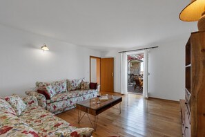 A living room with a floral sofa, a glass coffee table, and a wooden floor.